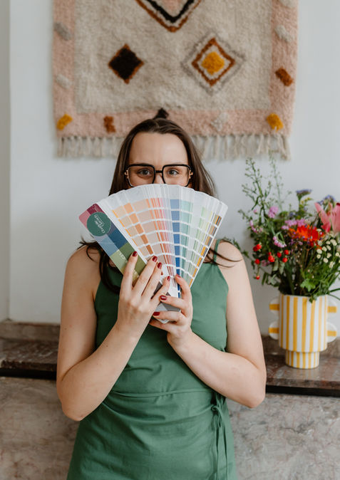 Interieurarchitecte Charlotte Claesen houdt een waaier met kleurstalen voor zich tijdens een branding shoot.