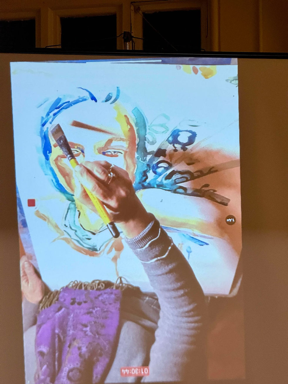 The painting begins to take on expressive characteristics as bold blue and red strokes enhance the contrast. The artist's hand is seen refining details around the eye and cheek.
