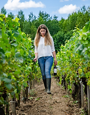 Vigneronne du Château de Côme marche entre les rangs de vignes