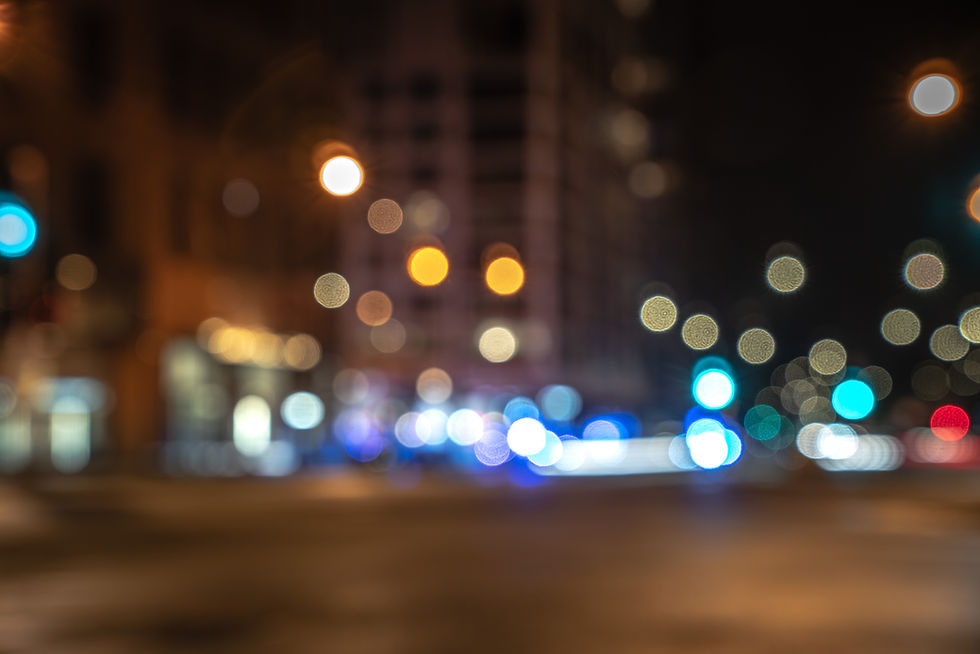 Blurred night-time cityscape with red and blue emergency lights in long exposure, evoking a fast-moving incident scene