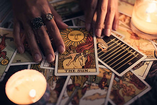 arot cards arranged on a reading table surrounded by candles.