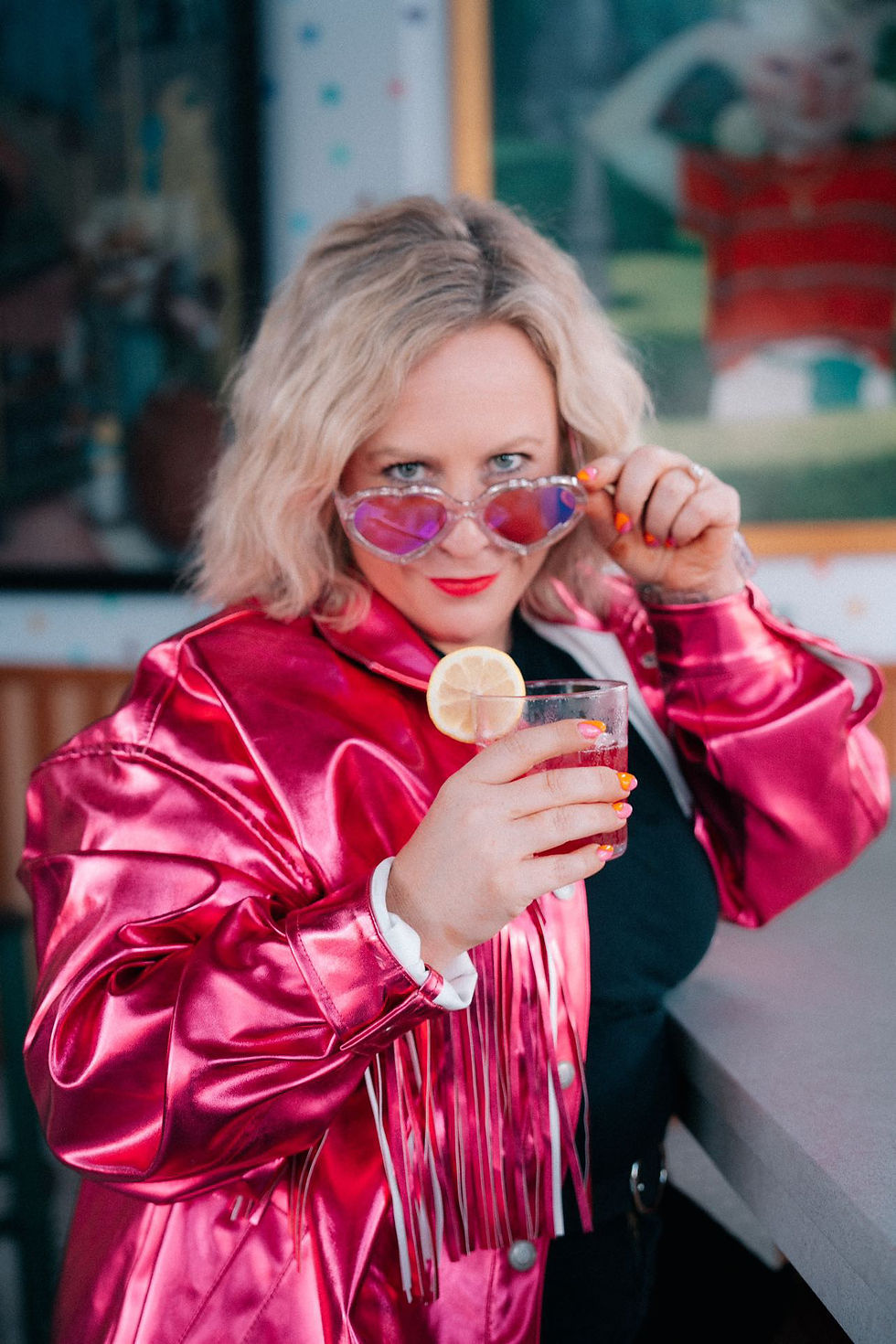trendy woman sipping drink in hot pink jacket