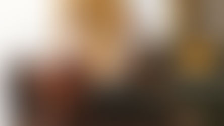 Man and woman sitting back-to-back on a sofa, arms crossed, looking away. Yellow curtains, cushions, soft light, tense mood.