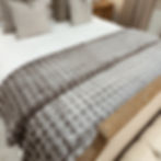 Raffled Taupe Throw styled on an end of a bed.