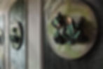 Wall with classic wainscoting, containing green Arte wallpaper on which a circular artwork with frogs is attached.