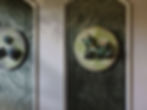 Wall with classic wainscoting, containing green Arte wallpaper on which a circular artwork with frogs is attached.