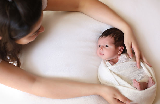 Close-up of newborn wrapped in cream blanket during studio session