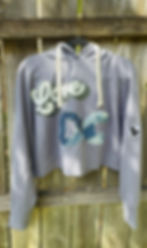 Upcycled Love cropped hoodie hanging on a wooden fence