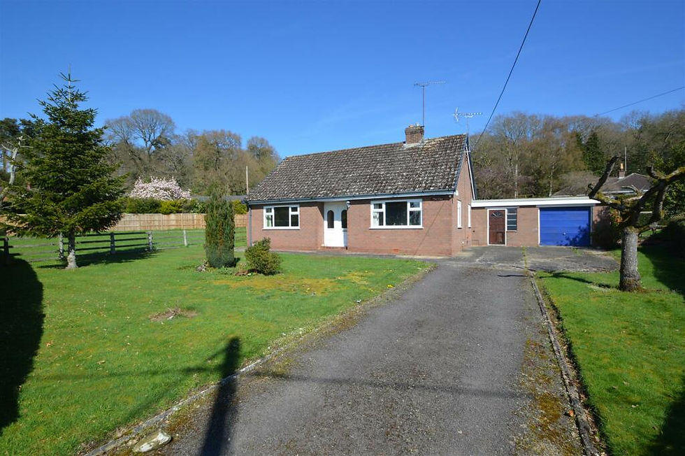 Brick house with blue garage, surrounded by green lawn and trees. Clear sky, long driveway. Peaceful rural setting.