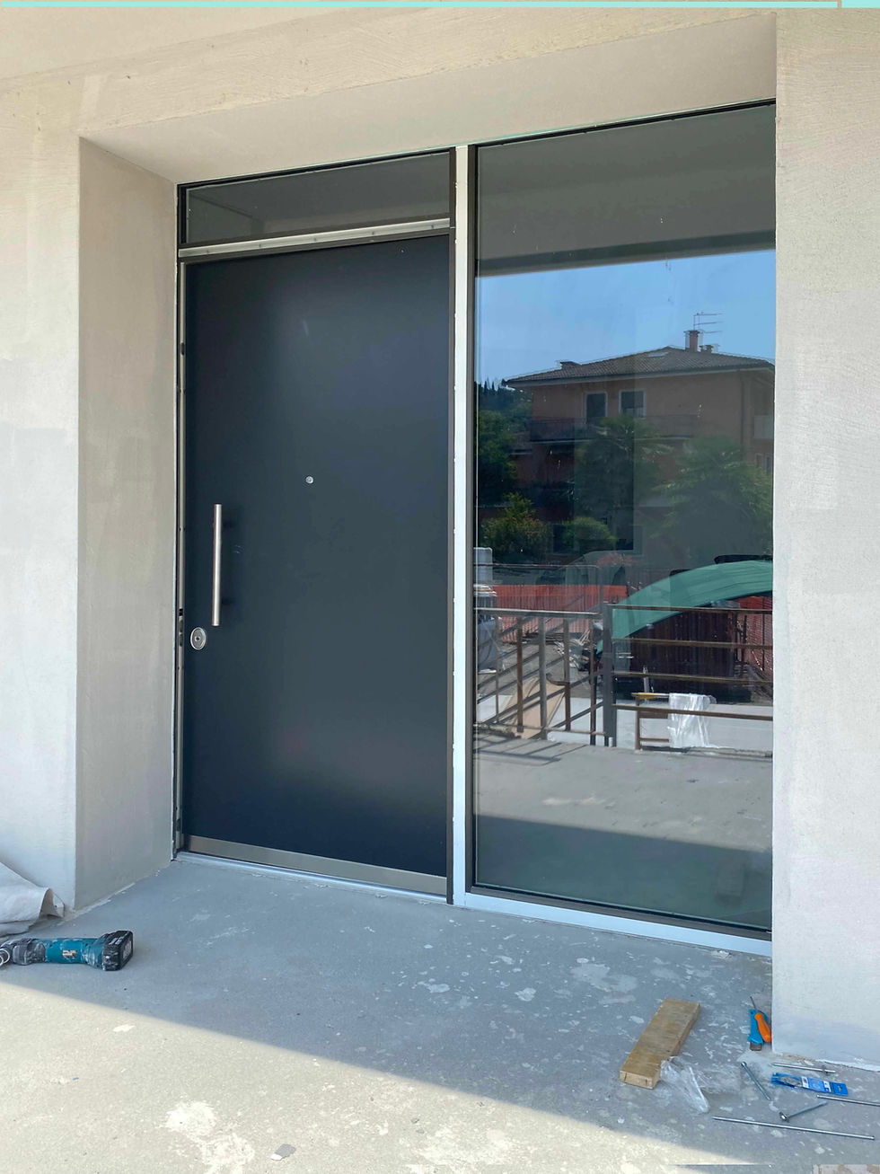 Porta blindata di design grigio scuro con vetrata laterale satinata. Elegante combinazione di sicurezza in acciaio, design minimale e luminosità per ingressi residenziali moderni.