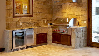 A fully equipped indoor grilling station is built of stone matching the 2-story fireplace in this 4-seasons addition