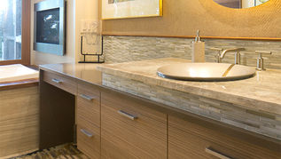 Mid-Century Modern vanity built with reconstituted veneer and manufactured quartz counter top. The sink sits on a riser made of natural granite and tile from the backsplash.