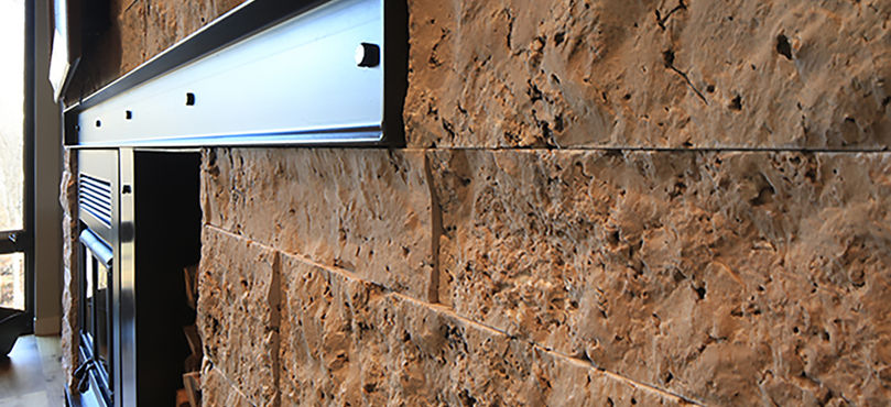 Closeup of Travertine stone veneer fireplace with steel beam.