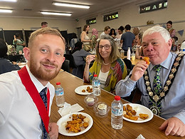 Witham Mayor and Deputy Mayor Cllrs Paul Heath and Jack Coleman sat at a table together with Cllr Joan Coleman, enjoying a meal in a hall full of people