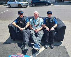 Witham Mayor Councillor Paul Heath sat on a sofa in Newland Street with a Police Community Support Officer on either side. This was for an event for Loneliness Awareness Week