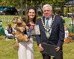Mayor Cllr Paul Heath in a suit and his Mayoral chains and a lady holding a dog in one arm, a certificate and rosette in the other at our dog show.