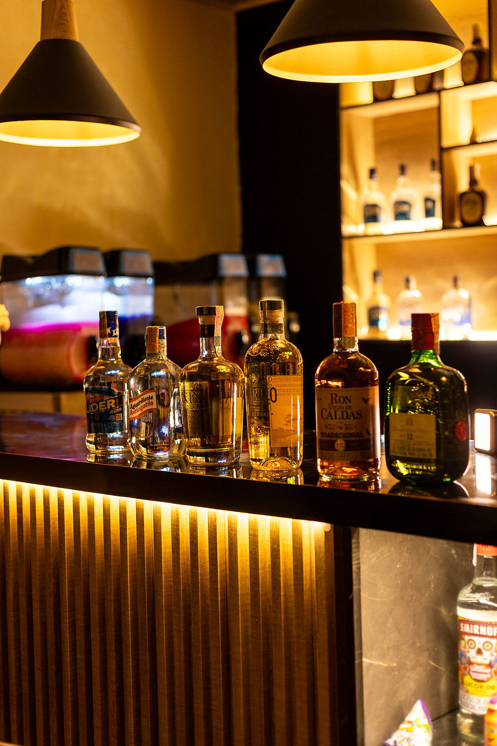 Botellas de licor en barra de bar iluminada