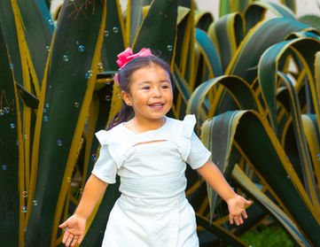 Niña sonriente frente a plantas de agave