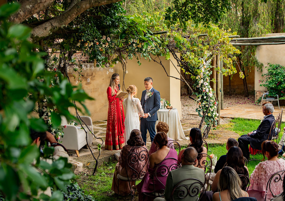 Ceremonia de boda en jardín, con pareja, oficiante e invitados.