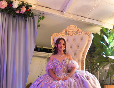 Quinceañera en vestido lila sentada en trono