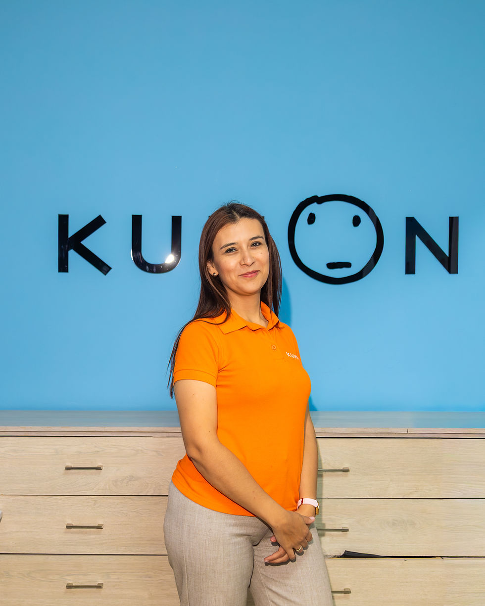 Mujer en polo naranja frente a logo KUON en pared azul.