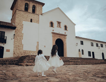 Niñas en vestidos blancos frente a iglesia.