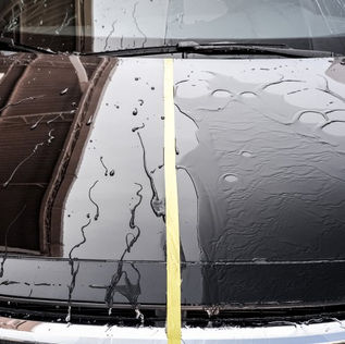 Comparação de capo de carro meio a meio, de um lado hidro repelência e do outro lado a agua não repele.