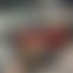 Profissional segurando embalagens do vitrificador SONAX em estúdio automotivo, com carro ao fundo exibindo alto brilho e proteção na pintura após aplicação.