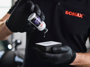 Profissional aplicando SONAX CC Pro: Coating cerâmico, pingando o líquido no aplicador de espuma para iniciar a proteção premium da pintura automotiva.