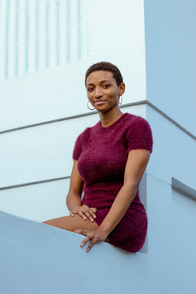 Woman in purple dress sitting on a balcony.