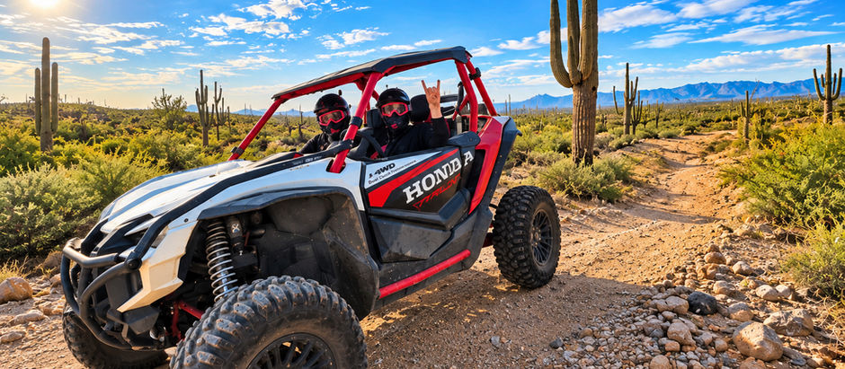 Two guests wearing helmets and goggles ride in a Honda Talon UTV on a rocky Sonoran Desert trail, surrounded by saguaro cacti and mountain views during a Desert Monsters Tours off-road adventure in Arizona.