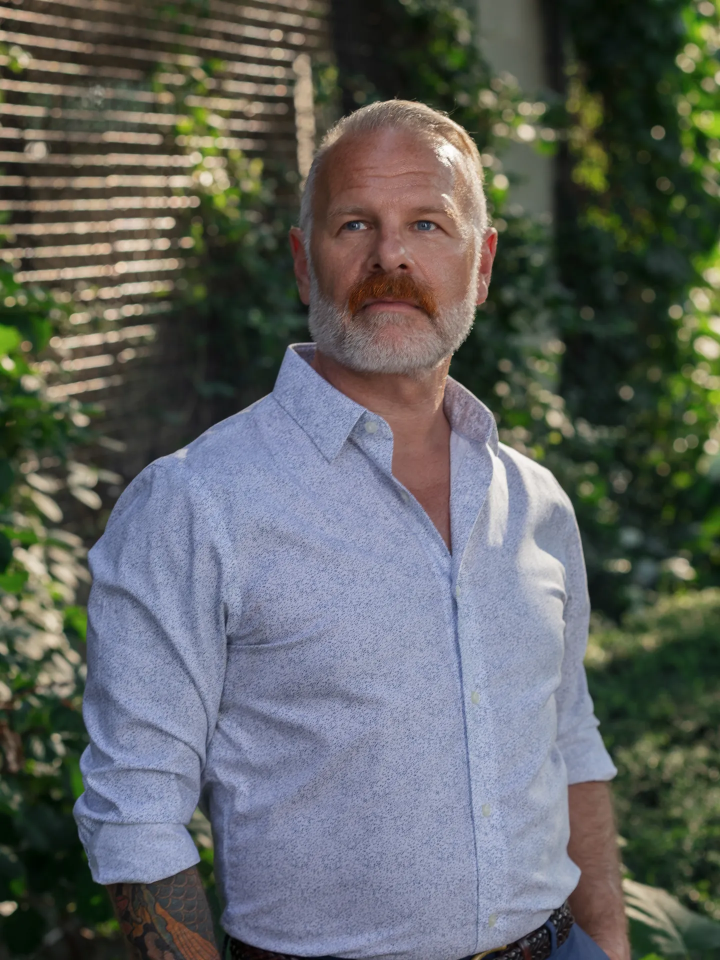 headshot of man in front of ivy wall
