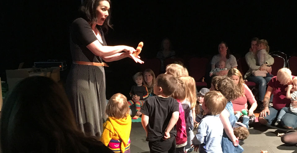 Hannah is surrounded by engaged children, watching her gingerbread man puppet come alive.