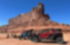 Polaris RZR and Canam Mavieric are parked in front of Monitor and Merrimack Buttes while the drivers enjoy lunch with their families. These famous buttes can be viewed from Ut Hwy 313.