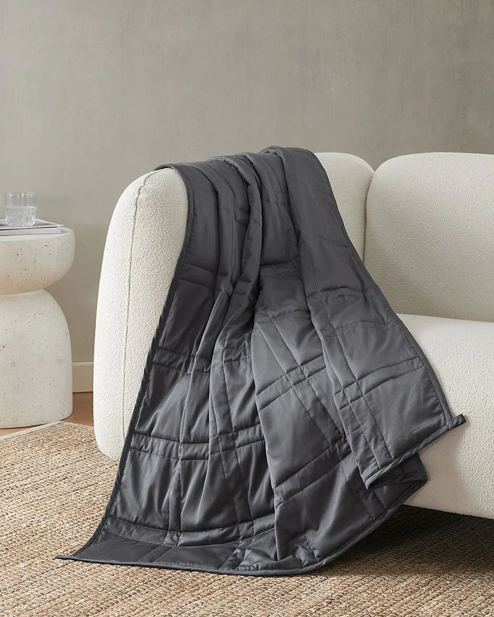 Midnight weighted blanket  by Baloo Living draped over sofa. 12lbs/5.4kg. Weighted blanket/throw for adults and older children. Luxury and extremely high quality. 100% cotton with glass microbeads and cotton filling.