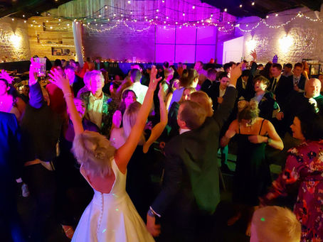 A busy dancefloor wedding, with people dancing to the sounds of a DJ.