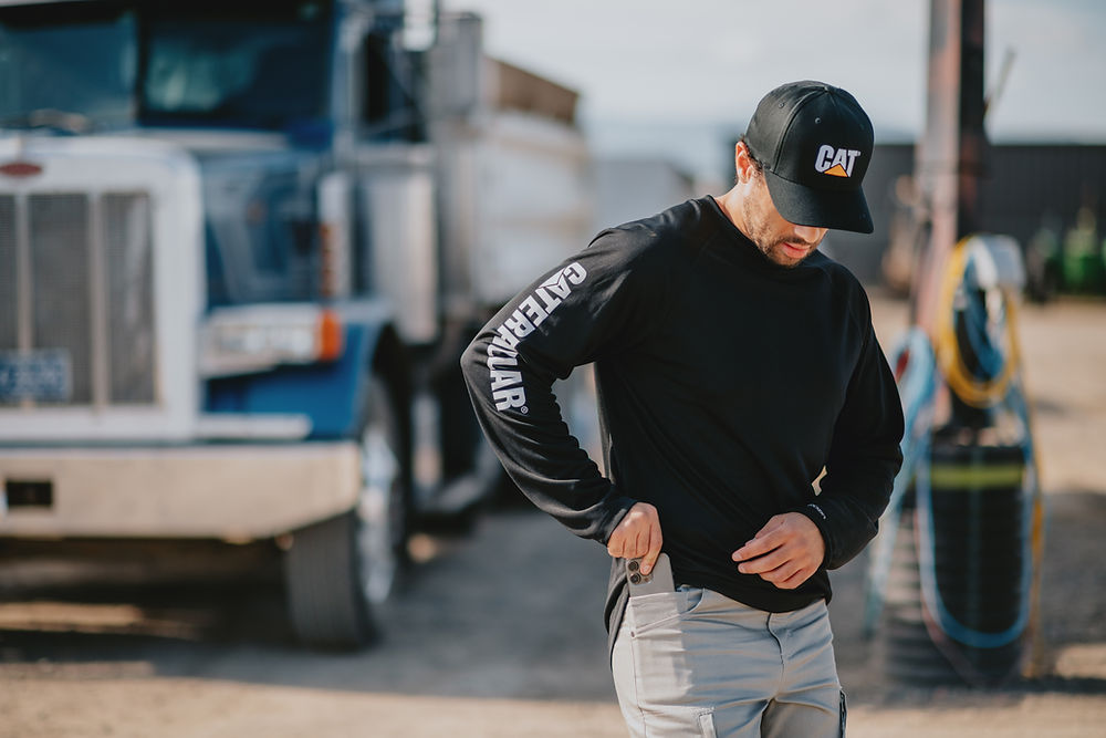 Man in CAT premium workwear shirt and cap by truck