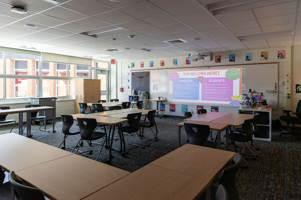 Classroom with tables, chairs, and a large screen.