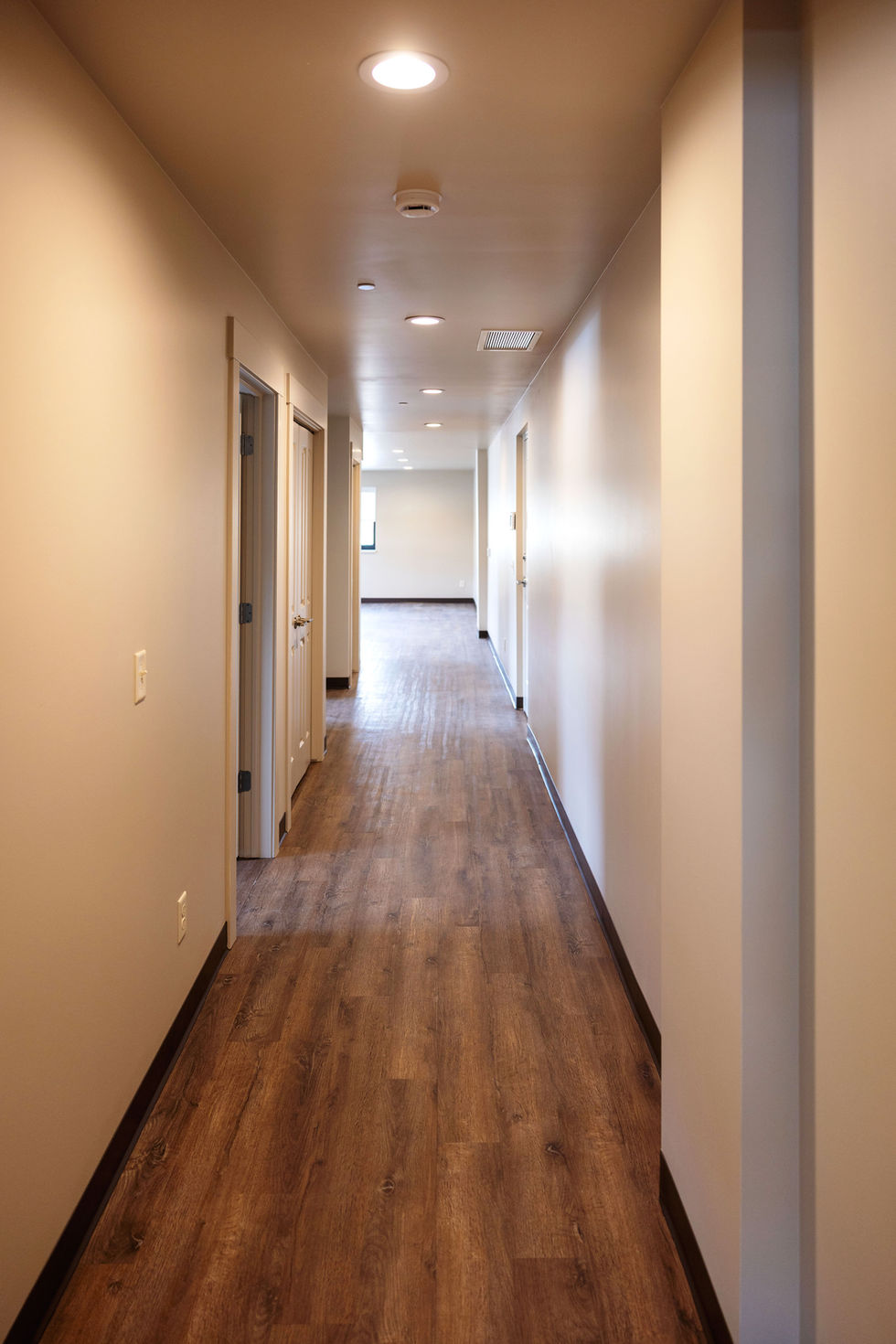 Long hallway with wooden flooring and white walls.