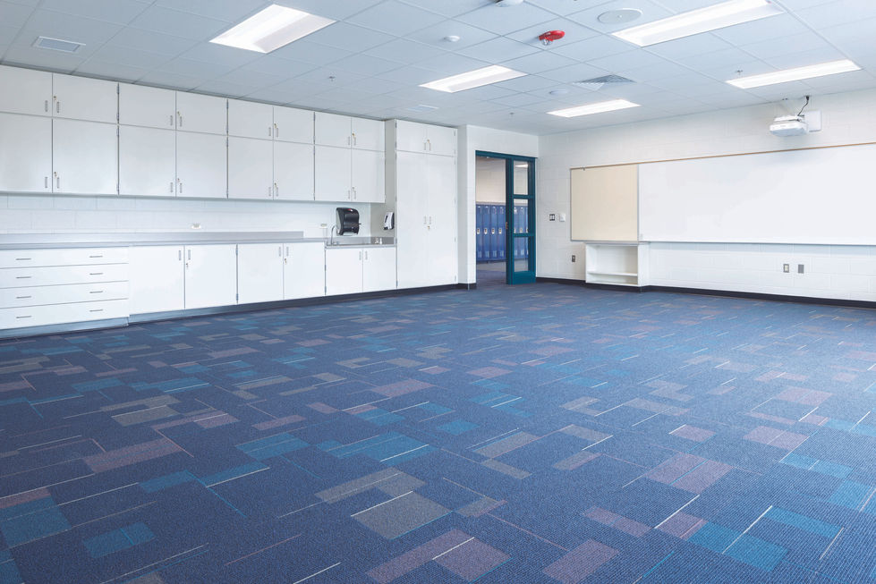 Classroom with blue carpet and white cabinets.