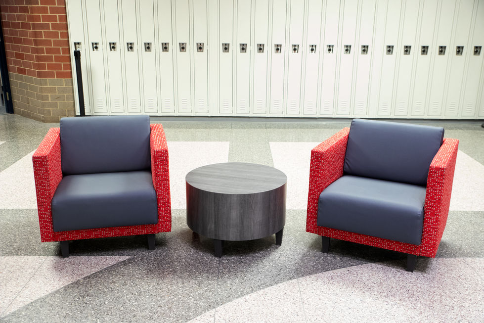 Two red chairs with a round black table.