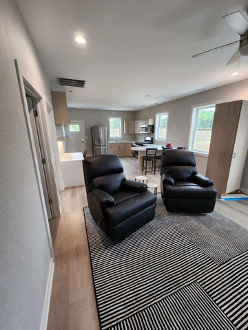 Modern living room with armchairs and kitchen area.