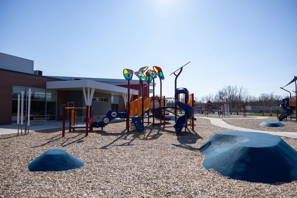 Elementary school playground with modern play structures and building exterior in background