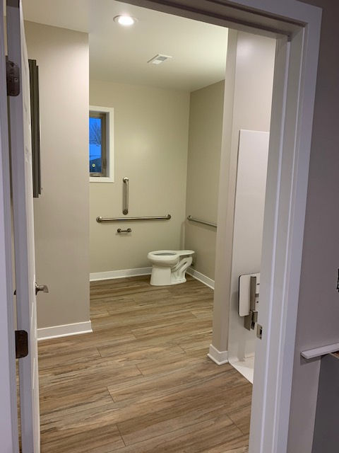 Bathroom with wooden floor and grab bars.