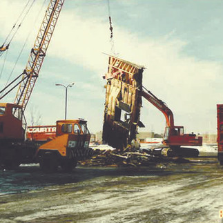 Construction crew using crane and heavy equipment to remove damaged structure during demolition phase of restaurant rebuild