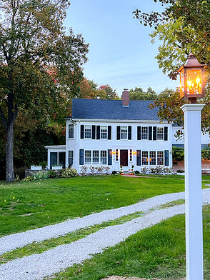 New England historic farmhouse in the fall with long driveway and lantern