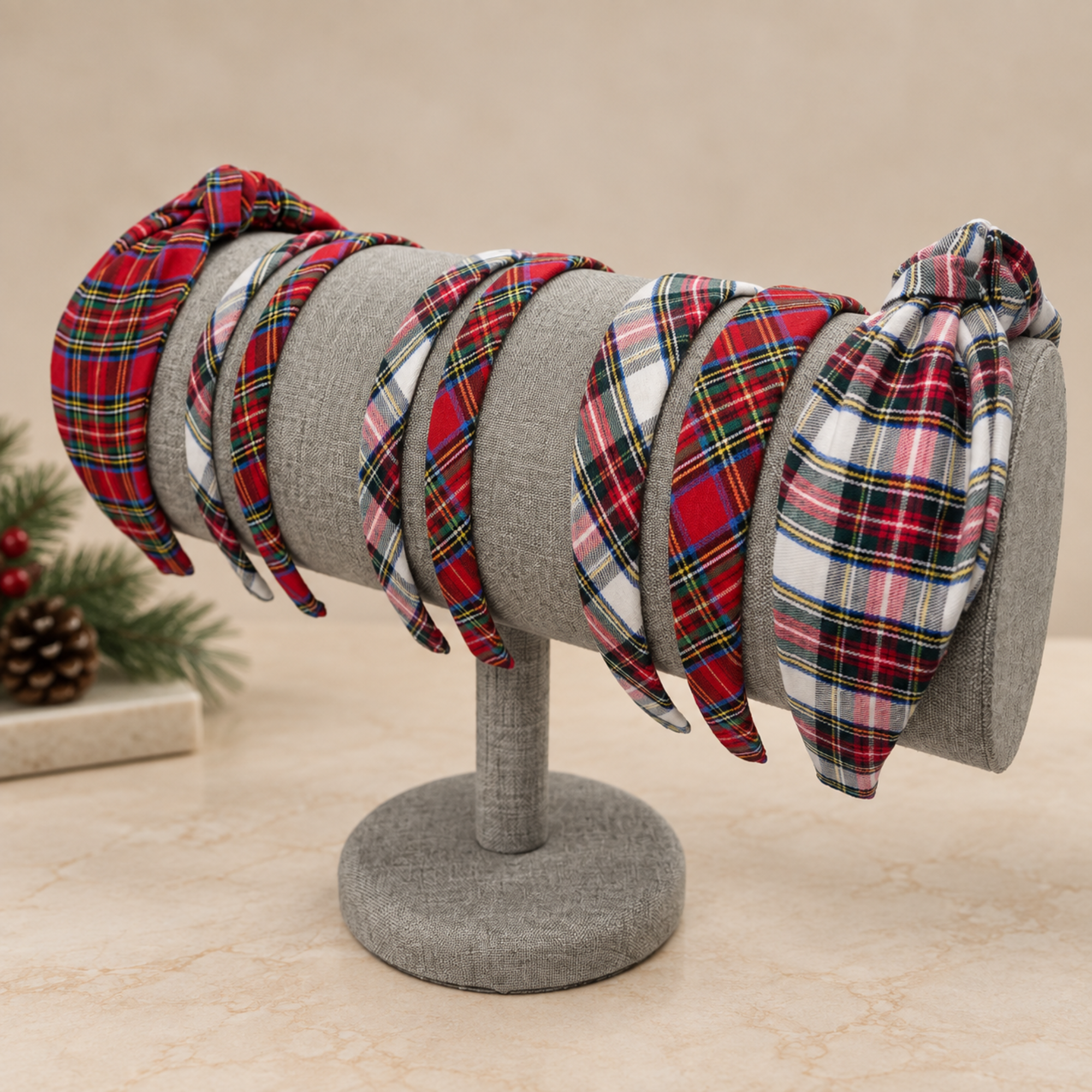 Red and ivory Stewart tartan plaid headbands in classic widths and top knot styles on a gray display stand.