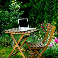 Cup of tea and laptop computer on a wooden table in a garden.jpg