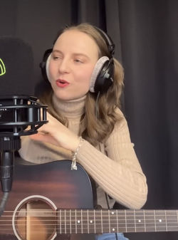 Rachel Makena with her acoustic guitar and headphones performing in a York radio studio