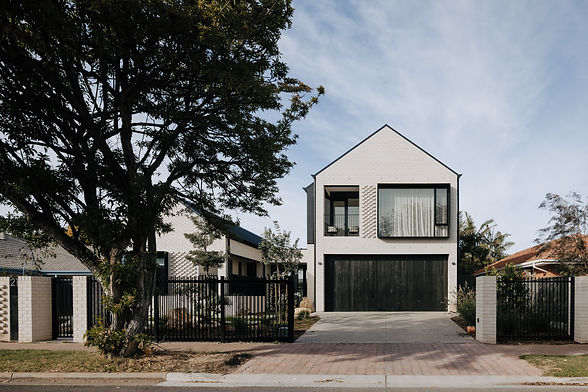Modern white house with dark garage door with expressed white bricks